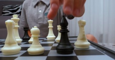 Gri tişört giyen çocuk satranç dönüşünü yapıyor. - Yakın çekim. Satranç tahtası seviyesinde çekildi. Cam sola hareket ediyor