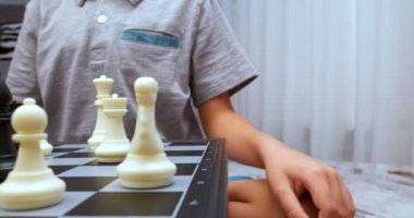 Gri tişört giyen çocuk satranç dönüşünü yapıyor. - Yakın çekim. Satranç tahtası seviyesinde çekildi. Cam sola hareket ediyor