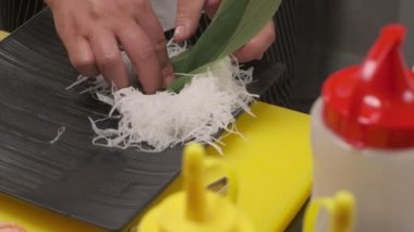 Daikon ile suşi süsleme, yapraklar ve siyah kare tabakta kafasıyla balık kesme. Yakın çekim.