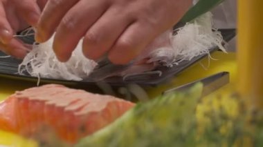 Daikon ile suşi süslemesi yapmak, yapraklar ve kafayla balık kesmek ve siyah kare tabakta balık dilimleri. Yakın çekim.