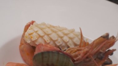 Daikon, limon dilimleri, yapraklar, kafayla kesilmiş balık ve siyah kare tabakta farklı türde kırmızı balık dilimleri ile suşi süslemek. Yakın çekim.