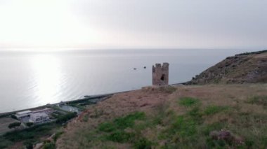İnsansız hava aracı, İtalya 'nın Amantea şehrinin panoramasıyla yıkılmış şato kulesine doğru uçuyor.