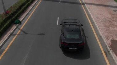 Bir İHA, deniz üzerindeki bir köprüde giden bir arabanın üzerinden uçuyor.