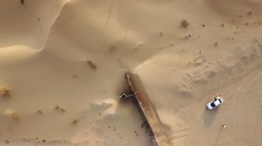 Çölün ortasında kumla kaplı bir yolda duran bir çiftin üzerinde İHA uçuşu.