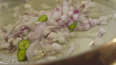 İnce doğranmış soğanlar kızartma tavasında yavaş çekimde kızartılır.