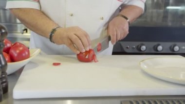 Şef domatesi yavaş çekimde keser, kapatır.