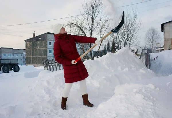Jonge vrouw reinigt het grondgebied van sneeuw. — Stockfoto