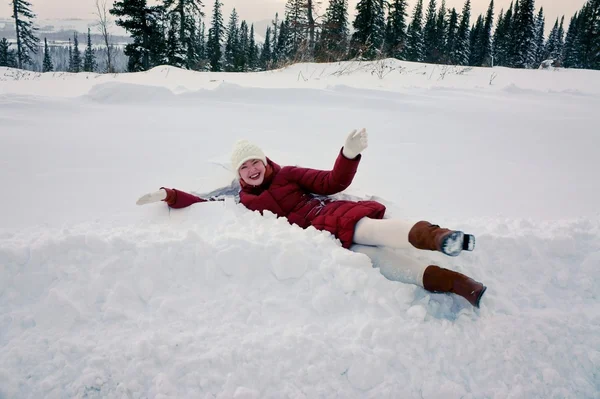 Meisje liggen in de snowbank in een winterdag. — Stockfoto