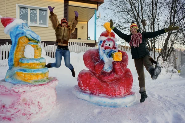 Meisjes springen in de buurt van de sculpturen van de sneeuw in de winter. — Stockfoto