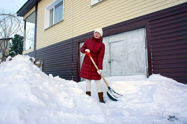 Meisje reinigt het grondgebied van sneeuw in de winter. — Stockfoto