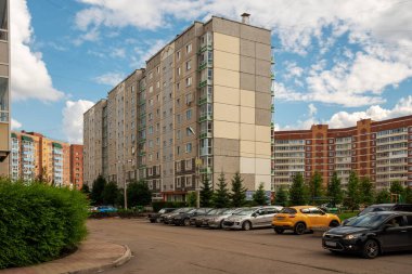 Krasnoyarsk, Krasnoyarsk Bölgesi, RF - 1 Temmuz 2021: Brezhnev döneminde inşa edilen on katlı konut paneli, yeni yüksek binalar arasında yer alıyor, arabalar yazın yakınlarda park halinde..