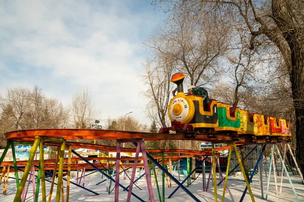 クラスノヤルスク クラスノヤルスク地域 2021年3月14日 子供列車は 都市遊園地の木々の間の雪のドリフトの上に高いレールに乗っています — ストック写真