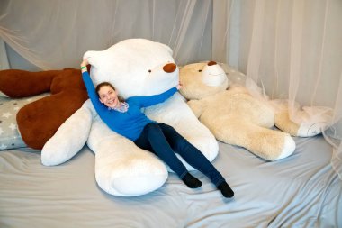 Genç bir kadın büyük bir oyuncak beyaz ayıya uzanır..