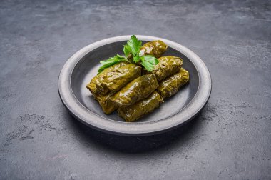 Lezzetli doldurulmuş üzüm yaprakları siyah tabakta maydanozlu dolma