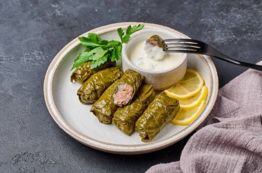 Geleneksel dolma maydanozlu ve limonlu, açık tabakta, peçeteli, siyah çatallı, dolma dikenli.