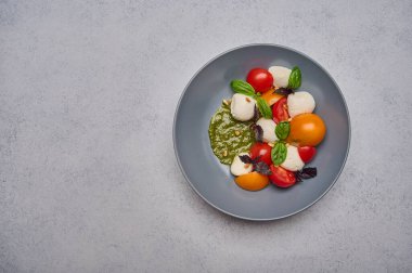 Olgun domatesli İtalyan caprese salatası, pesto, fesleğen ve mozzarella peyniri.