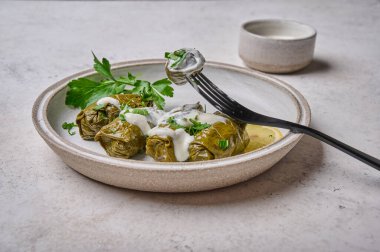 Dolma 'yı kapat, dolma üzüm yapraklarını pirinçle doldur ve acı kremalı et tabağına koy.