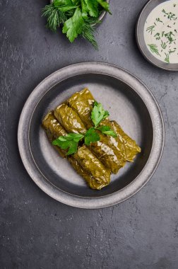 Dikey oryantasyon dolma, maydanoz, seramik renkli grafit tabakta ekşi kremalı tencere.