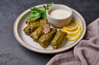 Dolma, pirinç, et, ekşi krema ve limonu beyaz tabakta keten peçeteyle kapat.