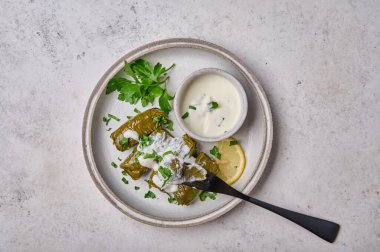 Üst manzara dolma, içi doldurulmuş üzüm yaprakları pirinçli et ve ekşi kremalı, siyah çatallı bir dolma parçasında et.