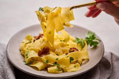 Kadın eli, mantarlı İtalyan makarnasıyla çatal tutuyor.