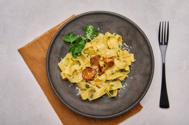 Siyah çatallı, siyah tabakta mantarlı, peynirli ve maydanozlu makarna. 