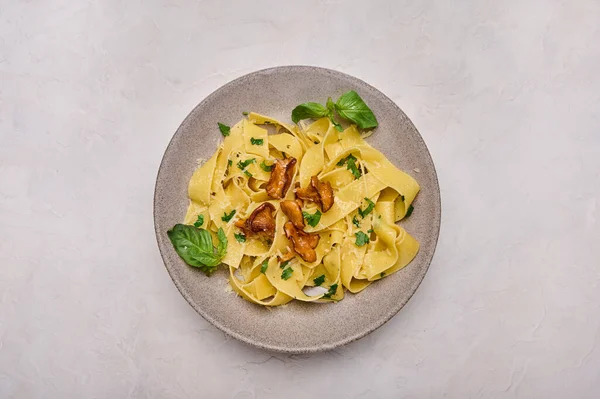 Horizontal orientation pasta pappardelle with mushrooms chanterelles, cheese and parsley on plate