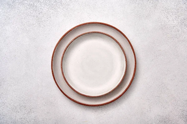 Empty two one in one white ceramic plates with brown rim on a light textured background — Stock Photo, Image