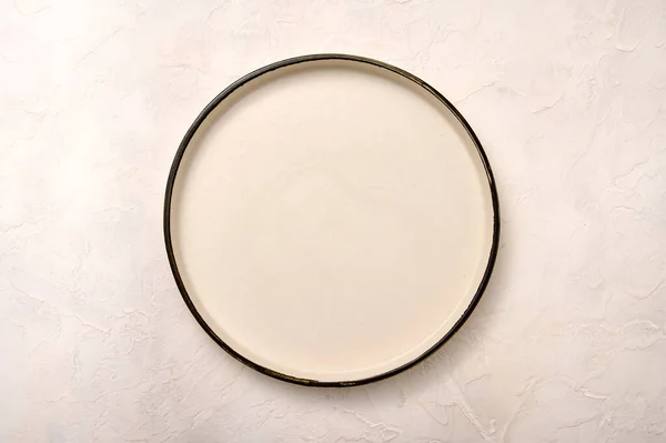 Placa de cerámica blanca vacía con borde negro sobre un fondo de textura clara —  Fotos de Stock