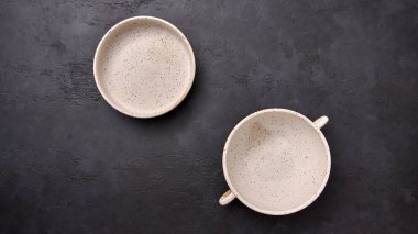 Düz, siyah desenli grafit arka planda kulplu ve tencereli bir çorba kasesi vardı.