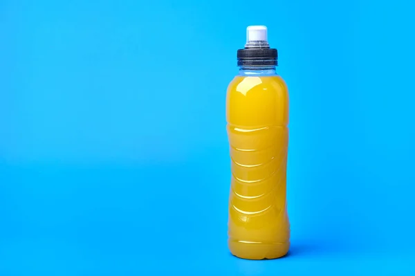 Isotonic energy yellow sport drink in plastic bottle on blue background