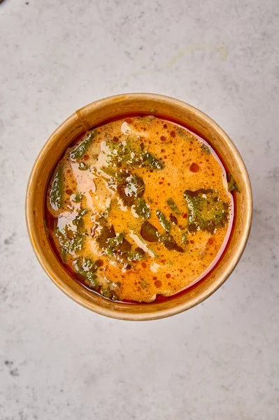 Sup Macro Tom Yam dengan salmon dan makanan laut dalam wadah padat kertas dengan latar belakang cahaya Stok Gambar