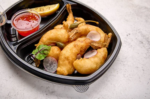 Fokus makro udang tempura fokus dengan saus cabai asam manis dan lobak dalam wadah plastik hitam Stok Foto
