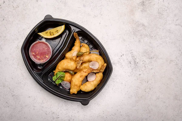 Udang tempura dengan saus cabai asam manis dan lobak dalam wadah plastik hitam Stok Foto Bebas Royalti