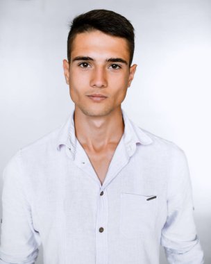 Beyaz arka planda beyaz gömlekli yakışıklı bir adam kameraya bakıyor..