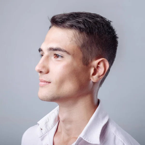 Yakışıklı adam beyaz bir gömlek ve kameraya seyir siyah kot giyen beyaz arka plan önünde ayakta.