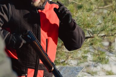 Kış ormanında av tüfeğiyle kamuflajlı avcı. Av kavramı. Karlı bir günde rezerv alan bir adam. Avcı karlı ormandaki bir silahtan nişan alıyor.