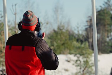 Kış ormanında av tüfeğiyle kamuflajlı avcı. Av kavramı. Karlı bir günde rezerv alan bir adam. Avcı karlı ormandaki bir silahtan nişan alıyor.