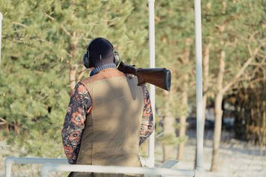 Kış ormanında av tüfeğiyle kamuflajlı avcı. Av kavramı. Karlı bir günde rezerv alan bir adam. Avcı karlı ormandaki bir silahtan nişan alıyor.