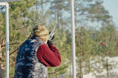 Kış ormanında av tüfeğiyle kamuflajlı avcı. Av kavramı. Karlı bir günde rezerv alan bir adam. Avcı karlı ormandaki bir silahtan nişan alıyor.