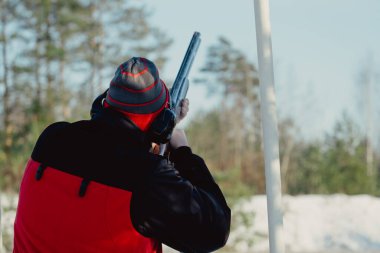 Kış ormanında av tüfeğiyle kamuflajlı avcı. Av kavramı. Karlı bir günde rezerv alan bir adam. Avcı karlı ormandaki bir silahtan nişan alıyor.