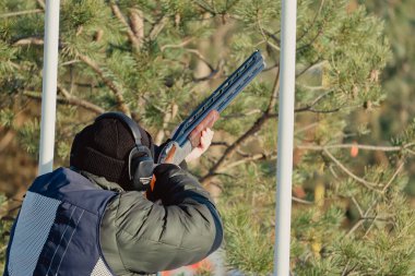 Kış ormanında av tüfeğiyle kamuflajlı avcı. Av kavramı. Karlı bir günde rezerv alan bir adam. Avcı karlı ormandaki bir silahtan nişan alıyor.