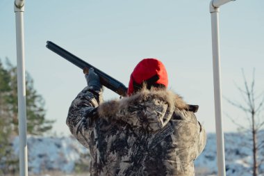 Kış ormanında av tüfeğiyle kamuflajlı avcı. Av kavramı. Karlı bir günde rezerv alan bir adam. Avcı karlı ormandaki bir silahtan nişan alıyor.