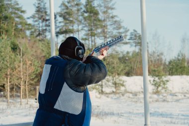 Kış ormanında av tüfeğiyle kamuflajlı avcı. Av kavramı. Karlı bir günde rezerv alan bir adam. Avcı karlı ormandaki bir silahtan nişan alıyor.