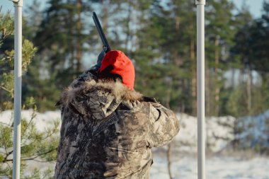 Kış ormanında av tüfeğiyle kamuflajlı avcı. Av kavramı. Karlı bir günde rezerv alan bir adam. Avcı karlı ormandaki bir silahtan nişan alıyor.