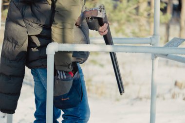 Kış ormanında av tüfeğiyle kamuflajlı avcı. Av kavramı. Karlı bir günde rezerv alan bir adam. Avcı karlı ormandaki bir silahtan nişan alıyor.