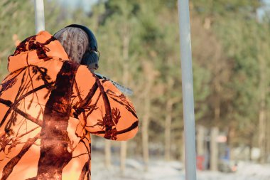 Kış ormanında av tüfeğiyle kamuflajlı avcı. Av kavramı. Karlı bir günde rezerv alan bir adam. Avcı karlı ormandaki bir silahtan nişan alıyor.