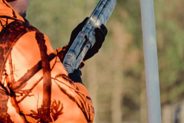 Kış ormanında av tüfeğiyle kamuflajlı avcı. Av kavramı. Karlı bir günde rezerv alan bir adam. Avcı karlı ormandaki bir silahtan nişan alıyor.