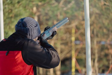 Kış ormanında av tüfeğiyle kamuflajlı avcı. Av kavramı. Karlı bir günde rezerv alan bir adam. Avcı karlı ormandaki bir silahtan nişan alıyor.