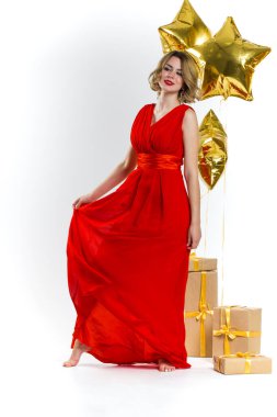 Kırmızı dudaklı, sarı kıvırcık saçlı ve gülümseyen zarif ve seksi bir bayanın parti fotoğrafı. Altın hava balonları ve hediyelerin arka planı. Satış konsepti